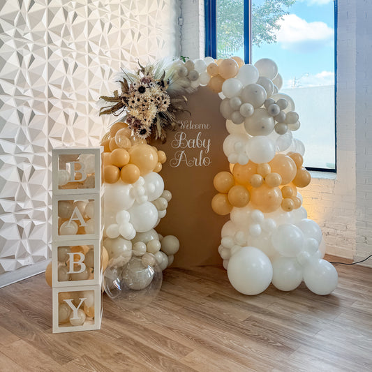 Large solid backdrop with floral accents and baby boxes