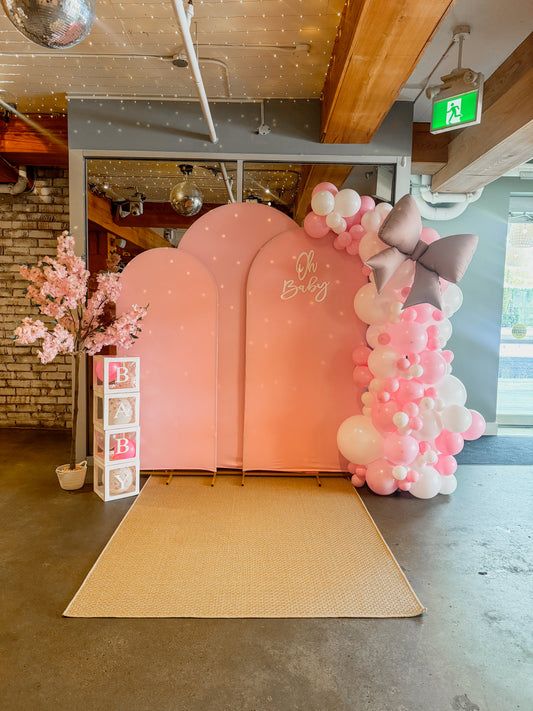 Triple arch fabric backdrop with side balloon garland, flower prop and baby boxes
