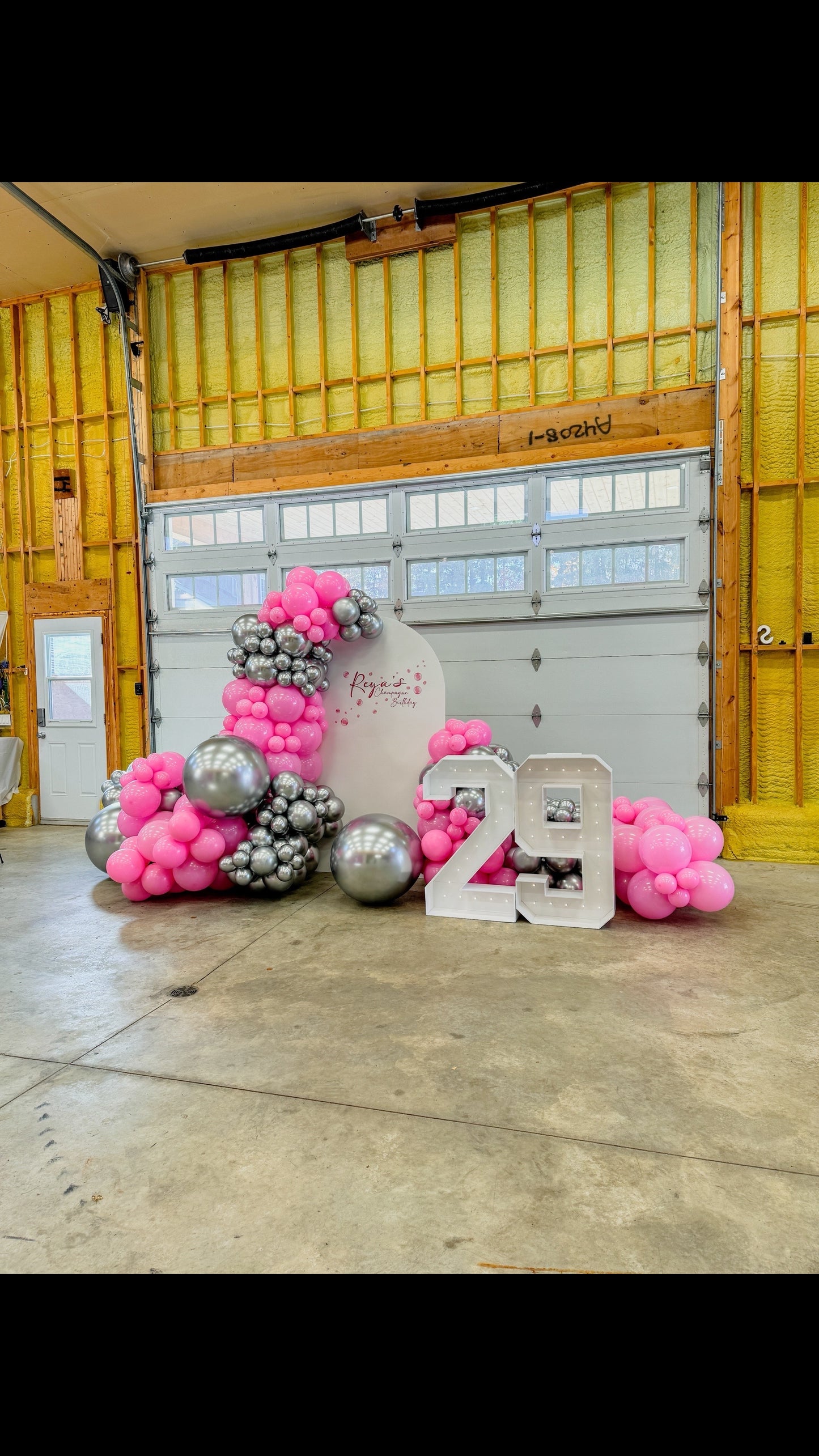 Large solid backdrop with cascading balloons on both sides and two marquee numbers