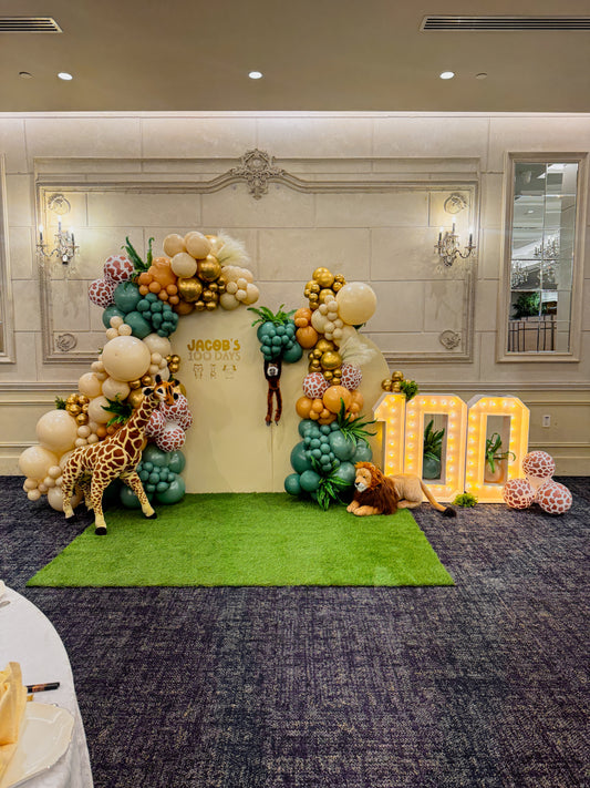 Double solid balloon filled backdrop with 3 light up numbers, grass floor, floral and stuffed animals